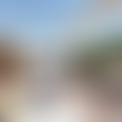 Rooftop terrace with sauna, hot tub, and loungers. Wicker chair, table with drinks, and greenery under a clear blue sky. Relaxing vibe.