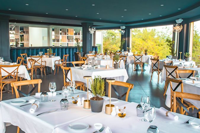 Capella Ubud restaurant: elegant dining room with tables set for guests