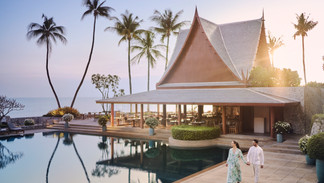 Couple walking by resort pool at sunset