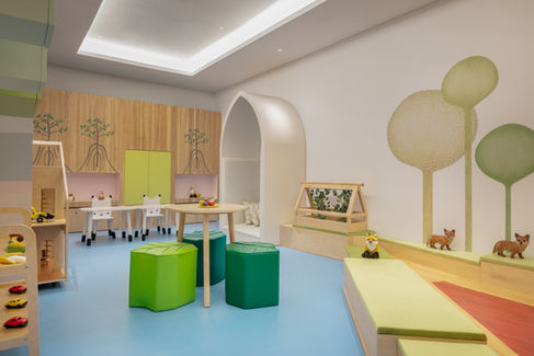 Bright kids' playroom with tables, chairs, and soft seating