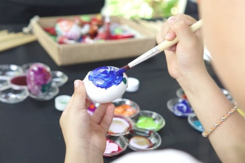 Hands painting an egg blue