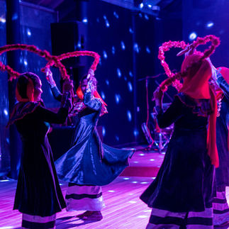 Dancers perform with swirling red hoops under purple stage lights
