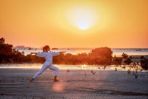 Woman practicing yoga at sunset on beach