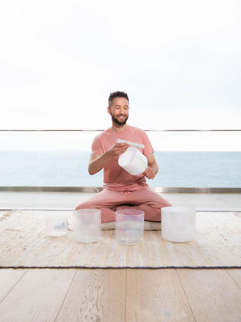 Smiling man playing crystal singing bowls outdoors