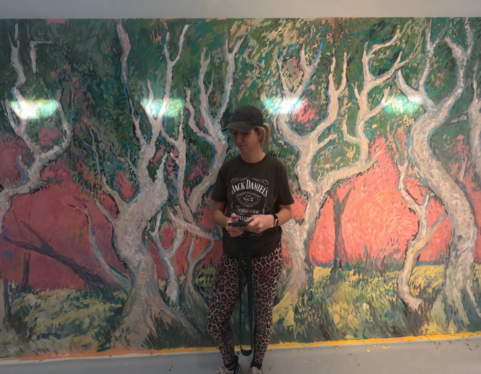 Professional mural artist Jen Stelco painting a large scale interior nature mural featuring abstract white trees and expressive foliage at Qattara Art Centre in Al Ain, UAE