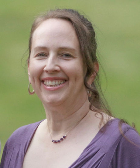 Karen Reid head shot with green background and purple dress