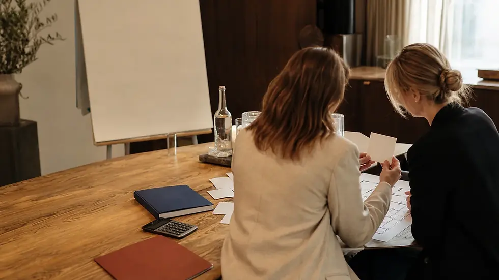 Two event organisers reviewing a keynote budget in a calm planning room.