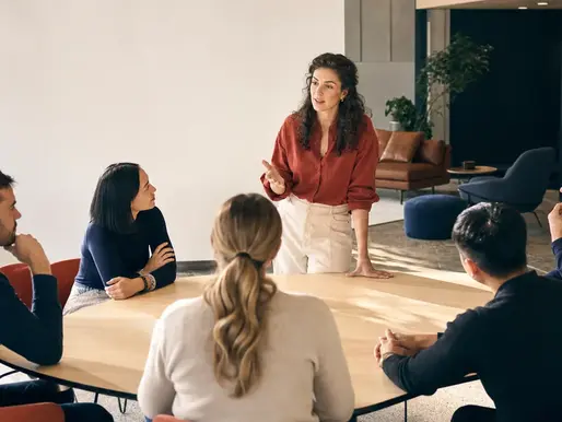 Professionals collaborating around a table in a bright workplace workshop.