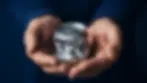 A pair of hands cradling a crumpled aluminium can, symbolising the value of waste in global recycling.
