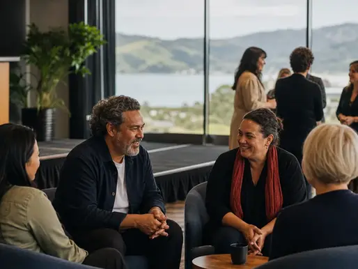 Education and workplace conference audience listening to a speaker in a bright New Zealand venue with water and mountains beyond the windows.