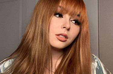 Woman with long strawberry blonde hair and straight bangs
