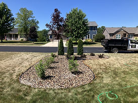 Plants and trees placed in a plant bed near a road.