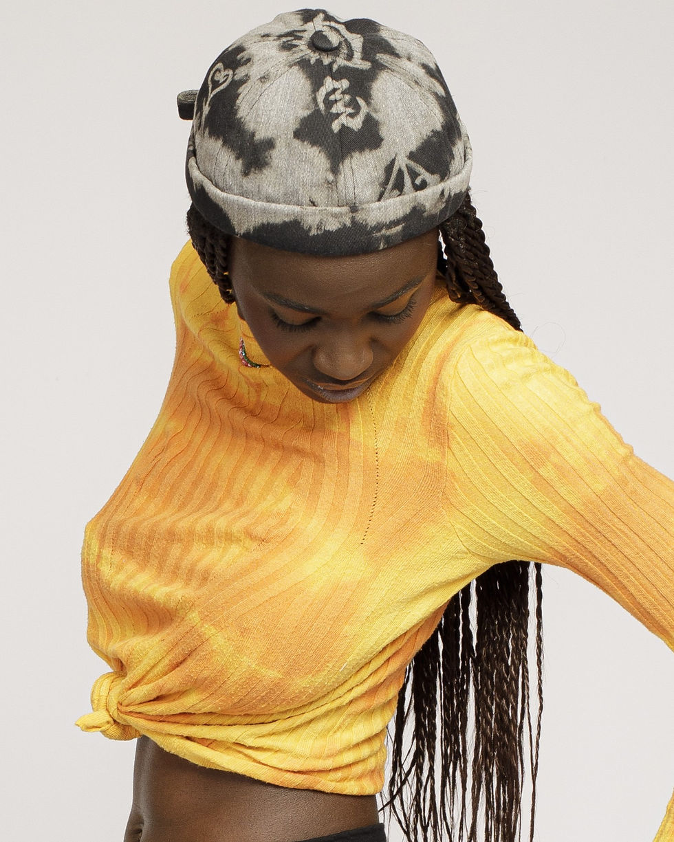 Brimless grey and black Adire hand-dyed Miki hat featuring a traditional Adinkra symbol, shown from multiple angles.