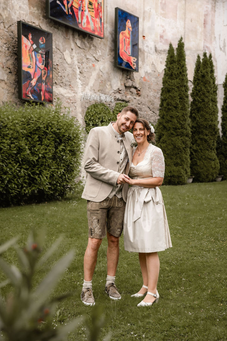 Braut und Bräutigam stehen Hand in Hand im Garten des Restaurants La Tavola in Enns während einer Hochzeitsreportage.