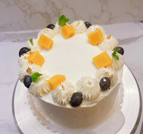 A Seasonal Fruit Cake decorated with fresh mango and blueberries.