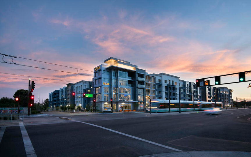Modern building and city street at dusk with a train