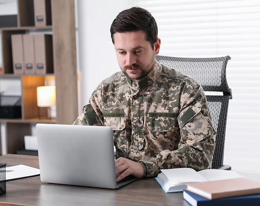 Man In Military Uniform Working On Laptop At Desk