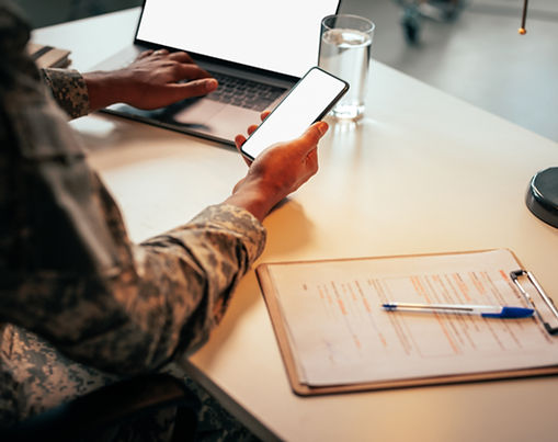 Military Personnel Using Smartphone And Laptop At Desk