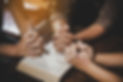 3 people praying over bible