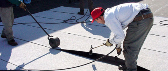 Roofing contractor applying an elastomeric roof coating