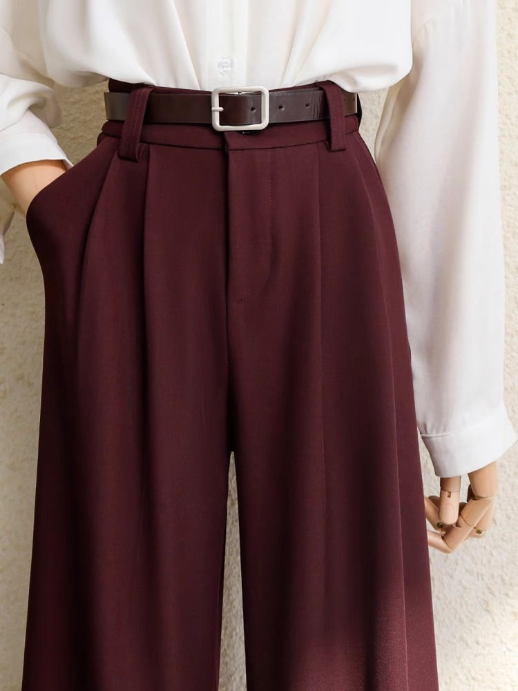 Calça de alfaiataria bordô com cinto fino e camisa branca.