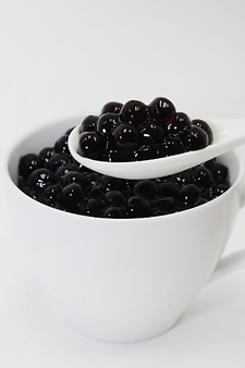 A spoon filled with fresh boba, showcasing their rich color and texture