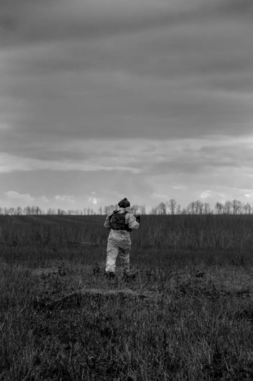 a black and white photo of a soldier running through a field .