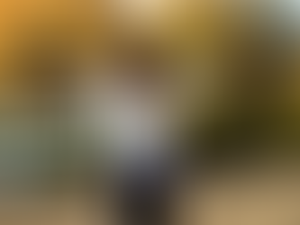 A woman standing outdoors with arms outstretched toward autumn trees, embracing freedom and joy in nature. Megan Haggett created this image.