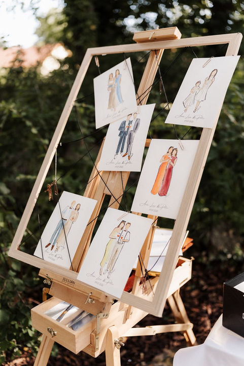 Hand-painted wedding guest portraits displayed on an easel at Romantik Landhotel 3Kronen in Franconia