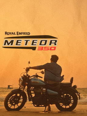 golden hour sunset and a guy is ditting on his royal enfield meteor 350 bike admirring the sunset