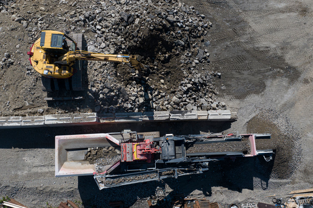 Aerial view of an excavator and a rock crusher on site.