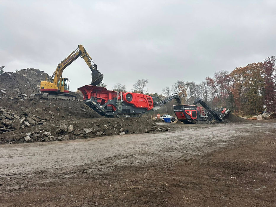Excavator loading heavy machinery at a work site