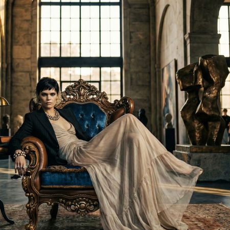 Erden Ekin tasarımı mavi kadife berjer, Lapis'in Rüyası, yüksek tavanlı galeri mekanında şık bir kadınla birlikte.