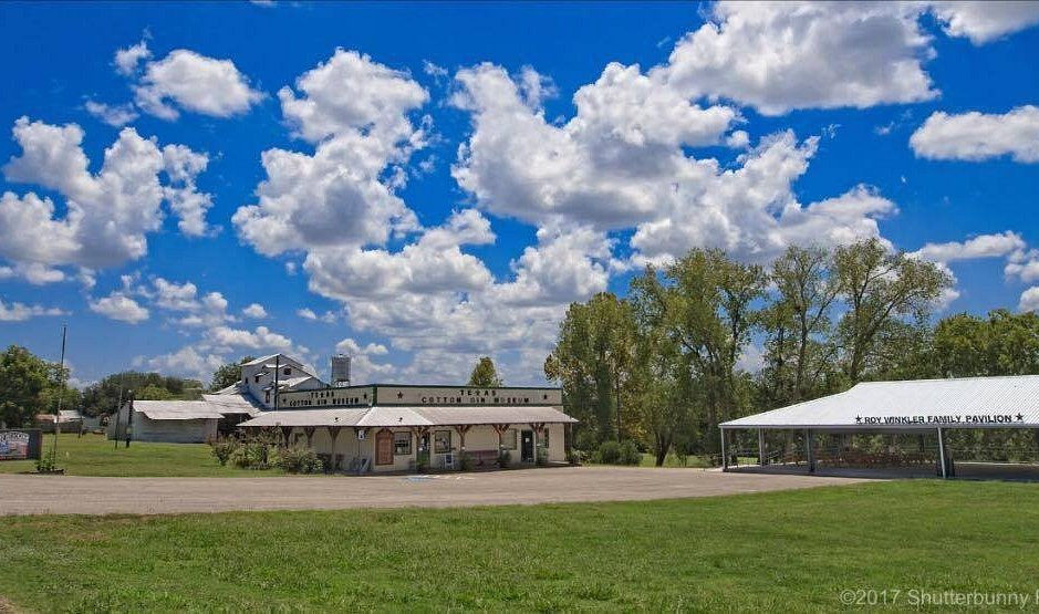 Texas Cotton Gin Museum buildings and pavilion under a blue sky.