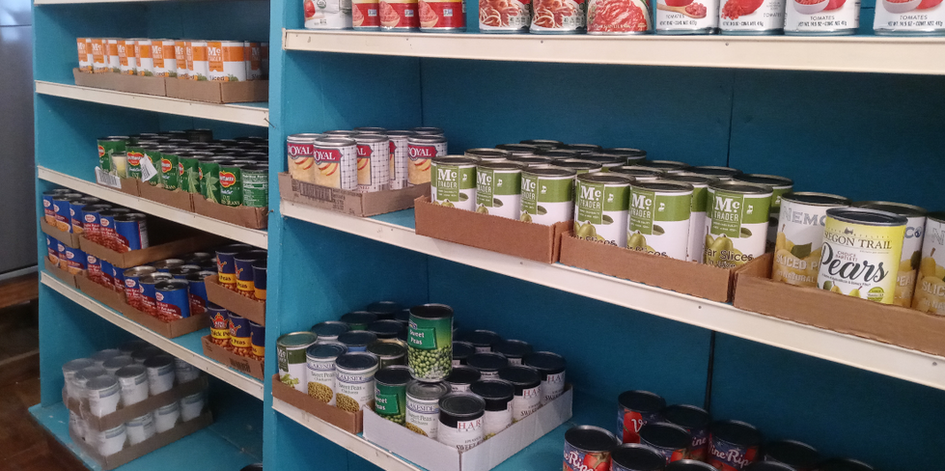 Canned goods organized on blue pantry shelves.