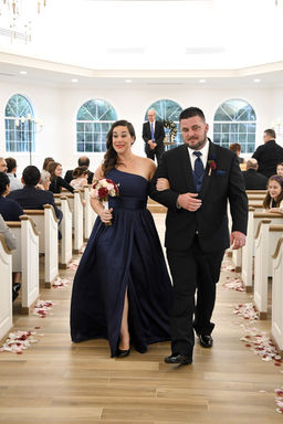 Bridesmaid walks with a man down the aisle at a wedding ceremony.