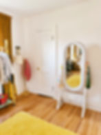 white wicker floor mirror near yellow rug and gold floor lamp