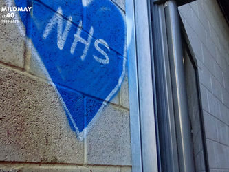 Graffiti of a blue heart containing the word NHS sprayed on a wall