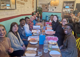 A group of Mildmay staff and students at a long dining table in a restaurant