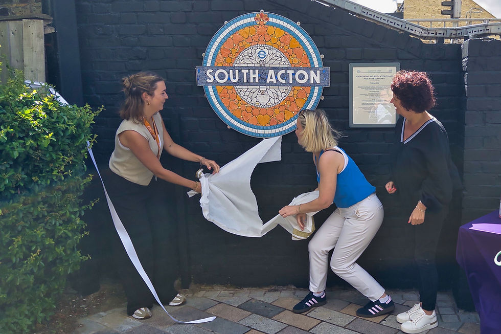 Three women unveil the mosaic 'South Acton' roundel