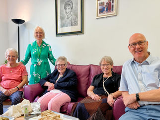 A group of 5 people sitting under Princess Diana's portrait at Mildmay Hospital.
