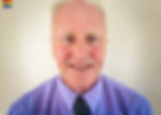 A portrait of Patrick, a smiling older man in a smart shirt and tie