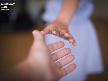 A nurse's hand reaches to grasp a patient's hand.