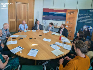 A group of people sit around a round table during a meeting