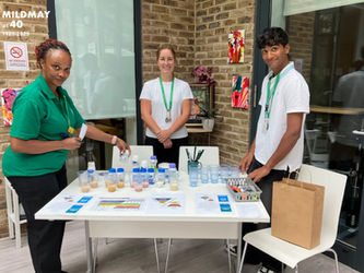 Three Mildmay staff around a table with leaflets charts and samples related to dysphagia education