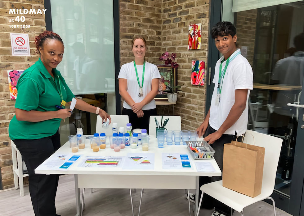 Three Mildmay staff around a table with leaflets charts and samples related to dysphagia education