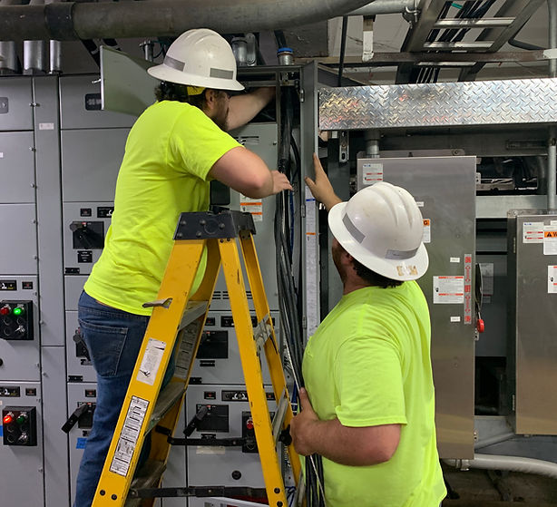 Two electricians in hard hats wiring electrical panels, electrical work in progress Electricalsu