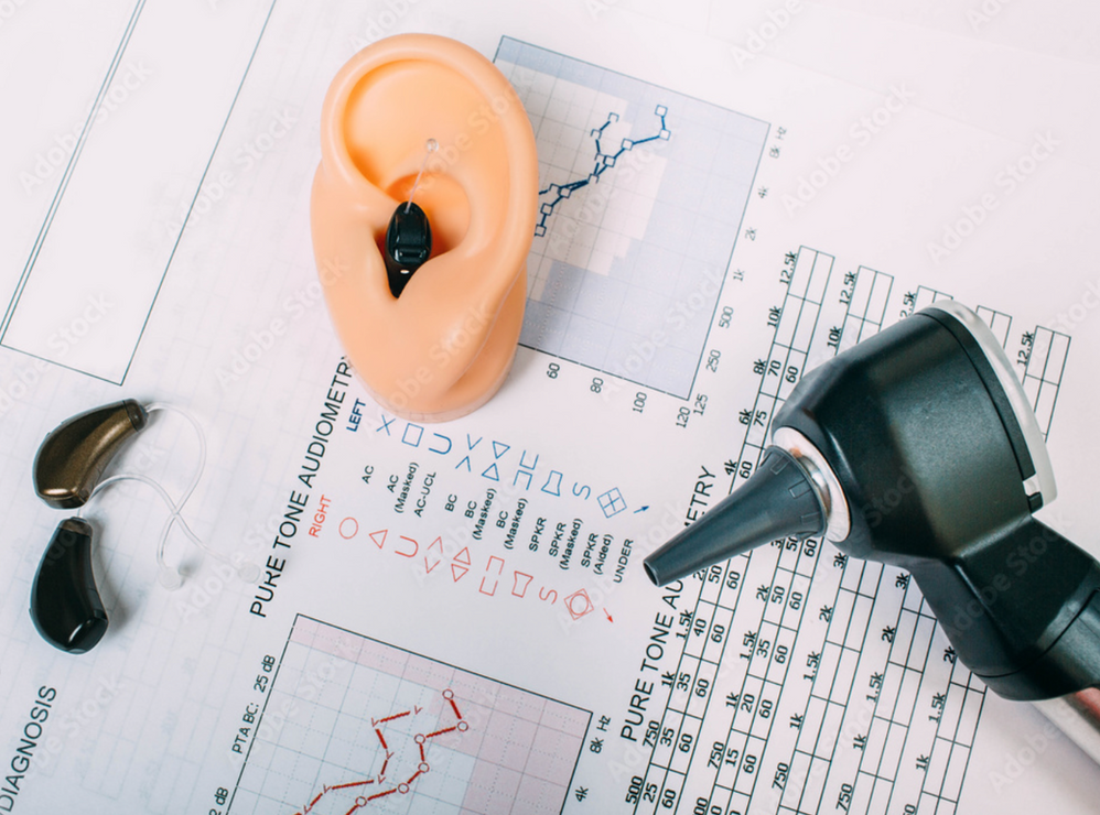 Ear model with hearing aids, otoscope, and audiology charts