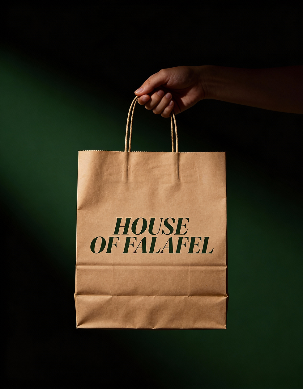 Hand holding brown paper bag with 'HOUSE OF FALAFEL' text.