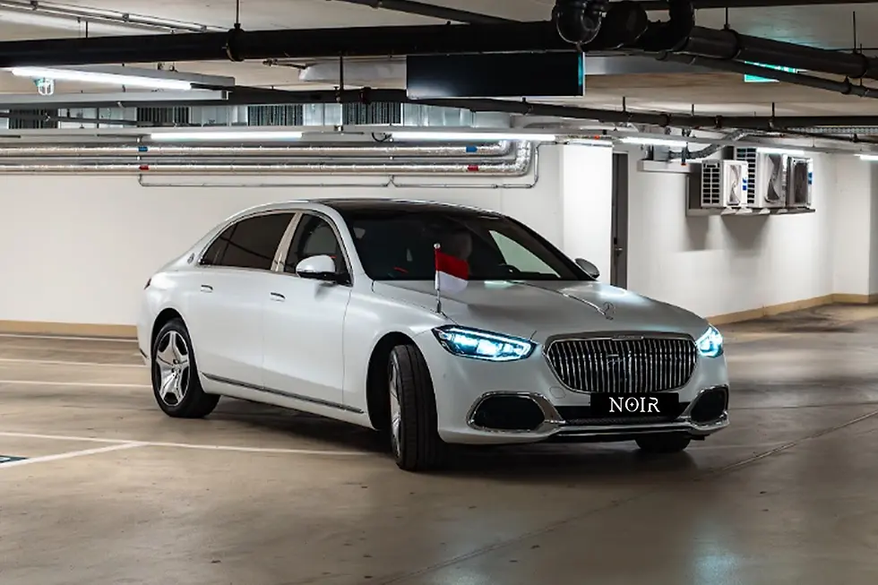 A white luxury limousine waits inside an indoor parking area for a private shopping transfer service.